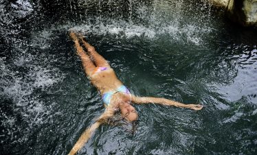 Jeune femme se relaxant dans les eaux thermales de La Fortuna au Costa Rica.